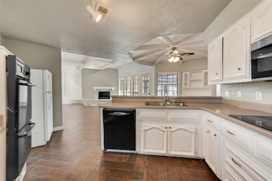 Kitchen with coffered ceiling, open floor plan, black appliances, beamed ceiling, and white cabinets