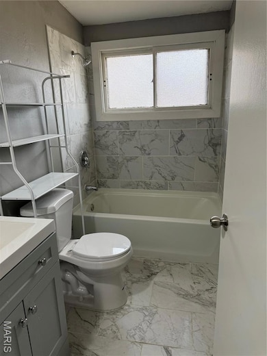 Full bathroom with shower / washtub combination, vanity, and light marble finish flooring