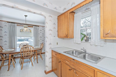 Kitchen featuring light countertops, decorative backsplash, wood cabinetry, and hanging light​​‌​​​​‌​​‌‌​​​‌​​‌‌​​‌‌​‌​​​‌‌​​‌​​​​​‌ fixtures