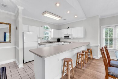 Kitchen featuring white appliances, a sink, a peninsula, baseboards, and crown molding