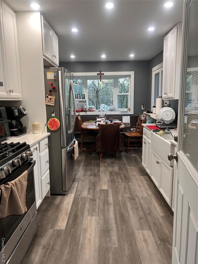 Kitchen featuring white cabinetry, fridge, dark wood-type flooring, stainless steel range, and recessed lighting