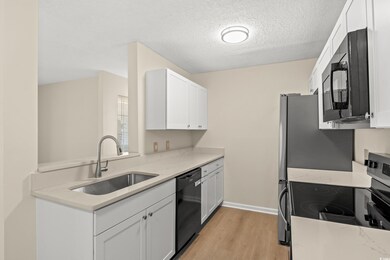 Kitchen with white cabinetry, light stone countert
