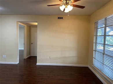 Empty room with dark wood finished floors and ceiling fan