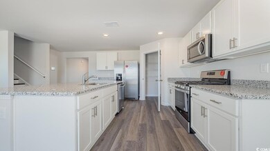Kitchen with sink, white cabinetry, wood-type floo