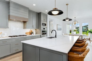 Kitchen featuring gray cabinets, tasteful backsplash, pendant lighting, light stone counters, and recessed lighting