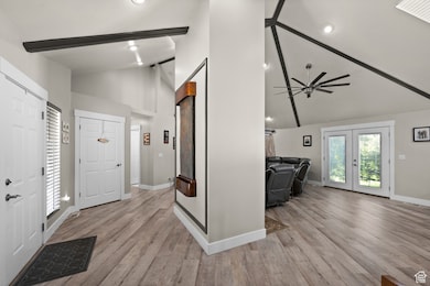 Entryway featuring light wood finished floors, high vaulted ceiling, recessed lighting, french doors, and beamed ceiling