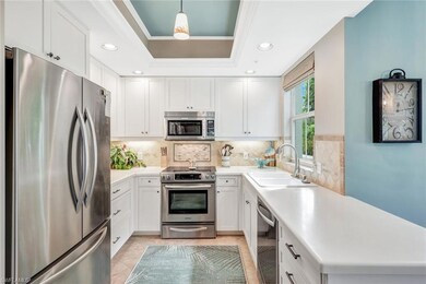 Kitchen featuring white cabinetry, sink, hanging light fixtures, backsplash, and appliances with stainless steel finishes