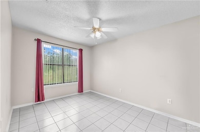 Empty room with a ceiling fan and a textured ceiling