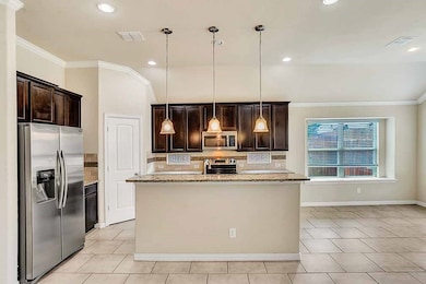 Kitchen featuring crown molding, dark brown cabinets, stainless steel appliances, hanging light fixtures, and light stone counters