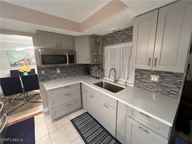 Kitchen featuring gray cabinets, sink, decorative backsplash, light tile patterned floors, and a textured ceiling