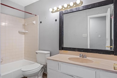 Bathroom with a textured wall, shower / washtub combination, and vanity