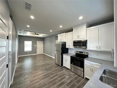 Kitchen with ceiling fan, white cabinets, appliances with stainless steel finishes, dark wood-type flooring, and backsplash