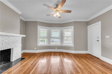 Unfurnished living room featuring crown molding, light hardwood / wood-style floors, and a brick fireplace