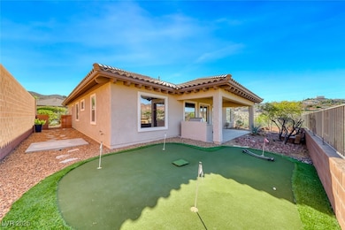 Back of property featuring a fenced backyard, a patio area, stucco siding, and a putting green