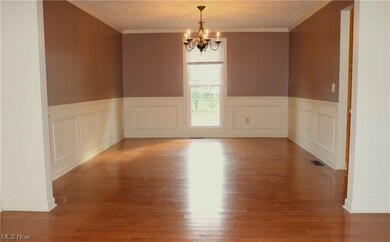 Spare room with crown molding, light hardwood / wood-style floors, and a chandelier