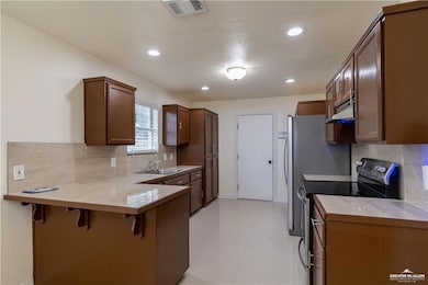 Kitchen featuring black electric range oven, a kitchen breakfast bar, decorative backsplash, under cabinet range hood, and a peninsula