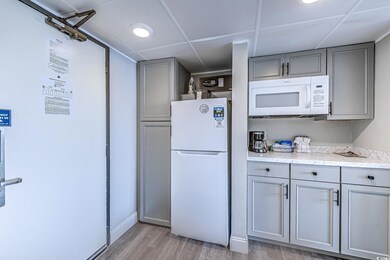 Kitchen featuring light wood-type flooring, light countertops, gray cabinetry, and white appliances