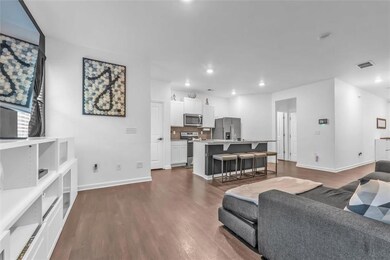 Living area with dark wood-style flooring, recessed lighting, and baseboards