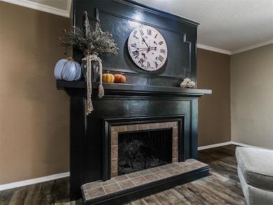 Detailed view of crown molding, a textured ceiling, wood finished floors, and a tile fireplace