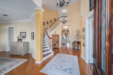 Elegant formal entry with wood flooring, high ceilings, stunning chandeliers, custom paint and beautiful wood staircase.