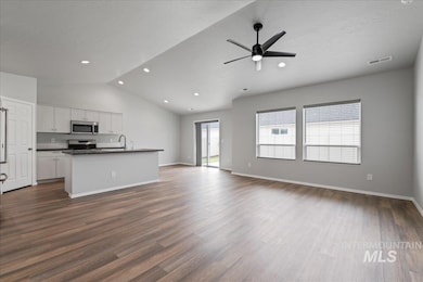 Unfurnished living room with a textured ceiling, dark wood-style floors, ceiling fan, vaulted ceiling, and recessed lighting