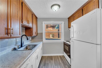 Kitchen with white appliances, dark wood finished floors, a textured ceiling, decorative backsplash, and brown cabinetry