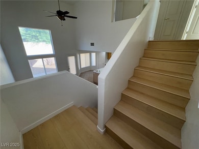 Stairway featuring a towering ceiling, wood finished floors, and ceiling fan
