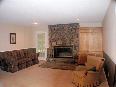 Great room has stone fireplace with gas logs, carpet, and   built-in cabinets.