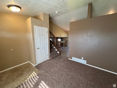 Carpeted spare room with a textured ceiling and stairs