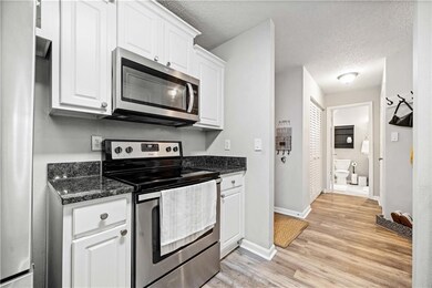 Kitchen with white cabinetry, light hardwood / wood-style floors, a textured ceiling, and appliances with stainless steel finishes