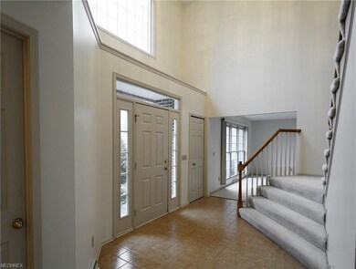 Foyer viewed to north  Half-bath door at left  Living room beyond  Carpeted stair ends rising on the right.