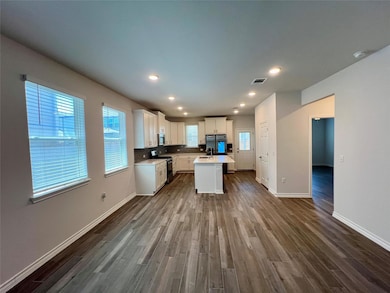 Kitchen with appliances with stainless steel finishes, dark wood-style floors, a center island with sink, light countertops, and white cabinets
