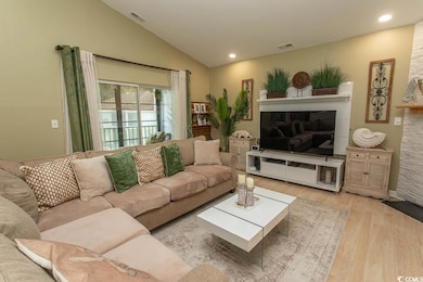 Living room with a fireplace, wood finished floors, lofted ceiling, and recessed lighting