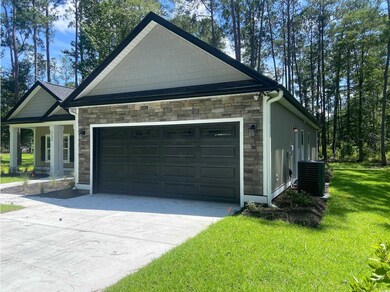 View of home's exterior featuring stone siding, concrete driveway, a lawn, and an attached garage