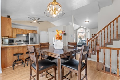 Dining area featuring light wood-type flooring, a chandelier, lofted ceiling, and stairway