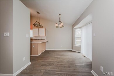 Unfurnished dining area with dark wood-type flooring, a chandelier, and lofted ceiling