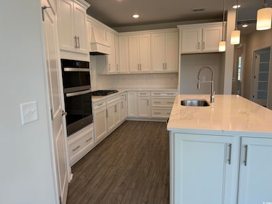 Kitchen with a sink, double oven, white cabinets, and recessed lighting