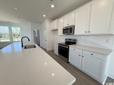 Kitchen featuring stainless steel appliances, recessed lighting, white cabinets, dark wood-style flooring, and light stone countertops
