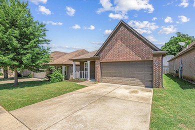 Traditional-style home featuring brick siding, a front yard, a garage, and concrete driveway