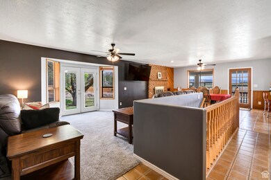 Living area with a ceiling fan, french doors, a textured ceiling, light carpet, and light tile patterned floors