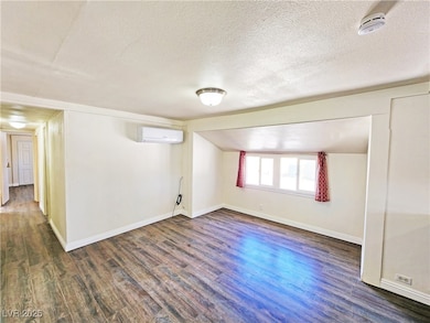 Empty room featuring a textured ceiling, a wall mo