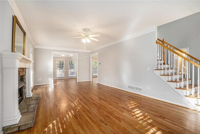 Unfurnished living room featuring crown molding, wood finished floors, stairs, a ceiling fan, and a stone fireplace