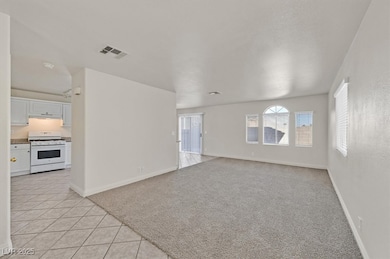 Unfurnished living room with light colored carpet and light tile patterned floors