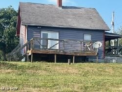 Side view of house featuring a yard and a wooden deck