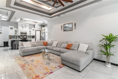 Living room featuring a tray ceiling and ceiling fan