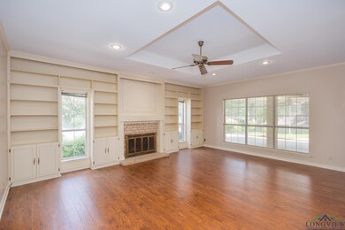 Unfurnished living room featuring a ceiling fan, dark wood-style floors, recessed lighting, a brick fireplace, and ornamental molding