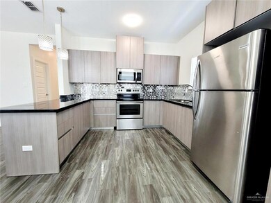 Kitchen featuring stainless steel appliances, dark countertops, a sink, modern cabinets, and a peninsula