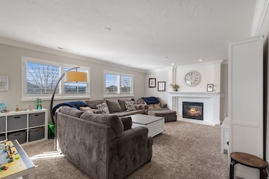 Living area featuring carpet, a fireplace with flush hearth, ornamental molding, and a textured ceiling