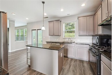 Kitchen with stainless steel fridge with ice dispenser, open floor plan, gray cabinetry, dark wood-style flooring, and recessed lighting