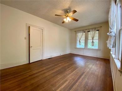 Spare room featuring a textured ceiling, dark woo